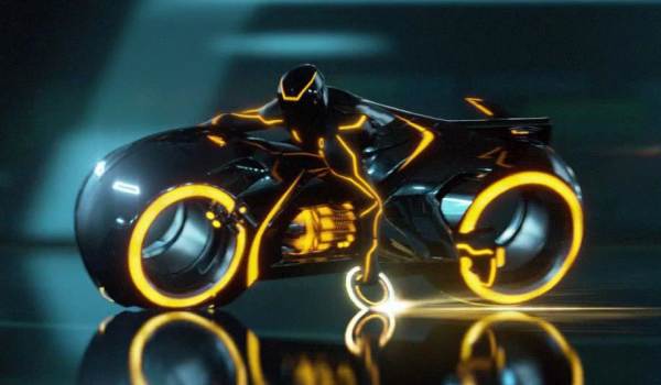 Sleek black Light Cycle with glowing orange neon rims and a rider in a matching light suit.