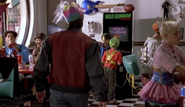 Movie still of Michael J. Fox as Marty McFly looking at the Wild Gunman arcade game in the 80s Cafe from Back to the Future Part II (1989)