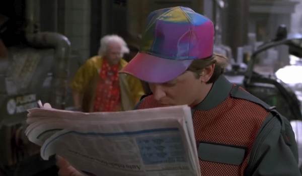 Movie still of Michael J. Fox as Marty McFly looking at a newspaper about his future son's arrest and Christopher Lloyd as Doctor Emmett Brown looking on in the sci-fi movie Back to the Future Part II (1989)
