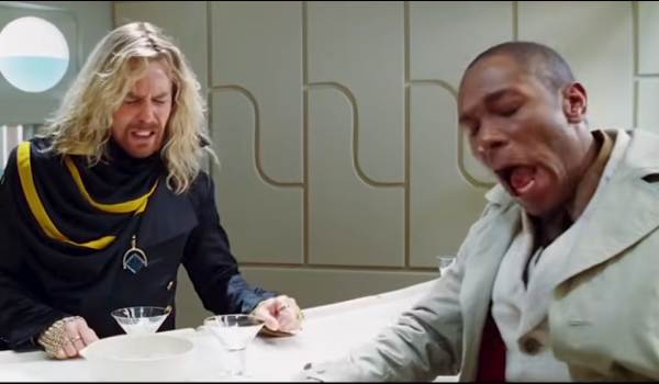 Sam Rockwell as Zaphod Beeblebrox and Yasiin Bey (Mos Def) as Ford Prefect from the 2005 film The Hitchhiker's Guide to the Galaxy, both reacting with dramatic, pained expressions while sitting at a futuristic white bar with cocktail glasses.