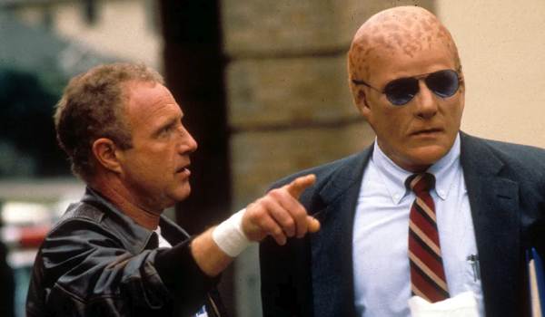 A still from the 1988 science fiction film Alien Nation showing James Caan as Detective Matthew Sykes pointing while speaking to Mandy Patinkin, who is in full makeup as the alien "Newcomer" detective Sam Francisco wearing sunglasses and a suit.
