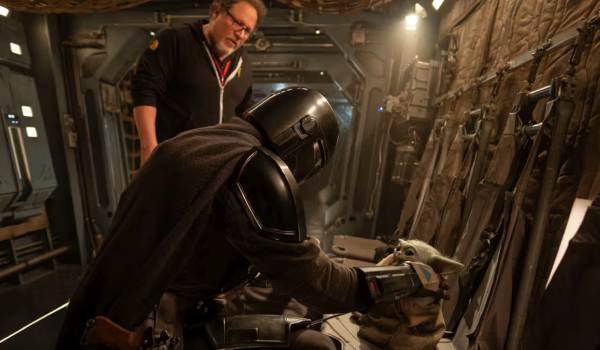  Behind-the-scenes photo from The Mandalorian and Grogu featuring director Jon Favreau watching as Pedro Pascal (Din Djarin) interacts with the Grogu animatronic.