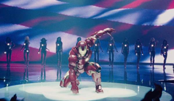 Iron Man performs a superhero landing at the Stark Expo in Iron Man 2, featuring Robert Downey Jr. as Tony Stark with the Ironettes in the background.