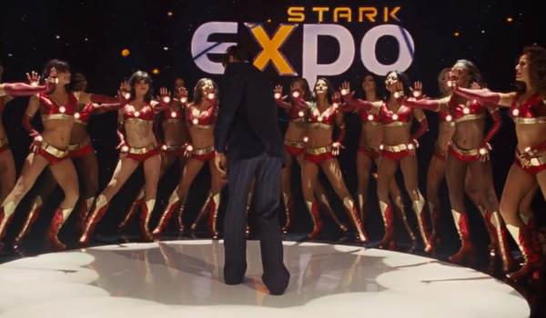 Robert Downey Jr. as Tony Stark makes a grand entrance at the Stark Expo in this scene from Iron Man 2 (2010). Flanked by the Ironettes in their signature red-and-gold armored dance costumes, the image perfectly captures Stark’s flair for showmanship and high-tech spectacle.