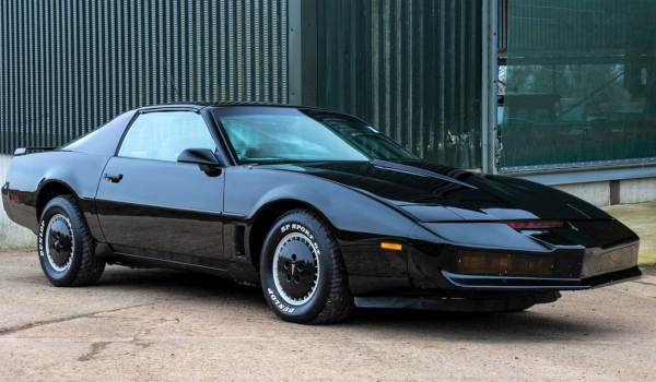Frontal three-quarter view of KITT, the modified black Pontiac Firebird Trans Am from Knight Rider, featuring the iconic red scanner light on the hood.