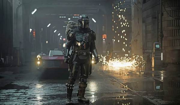  Pedro Pascal as the Mandalorian stands in a wet, neon-lit alley with Grogu on his back, while sparks shower down in the background.