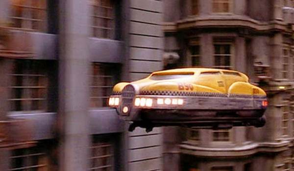 alt textSide view of Korben Dallas' yellow flying taxi from The Fifth Element cruising past city buildings.