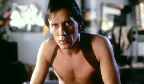 James Woods as Max Renn in the 1983 film Videodrome, shown shirtless with an intense, haunted expression in a cluttered apartment setting.