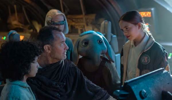Jod Na Nawood (Jude Law) sits with a group of young companions, including the small blue alien Neel, inside the cockpit of a starship from the 2024 series Star Wars: Skeleton Crew.