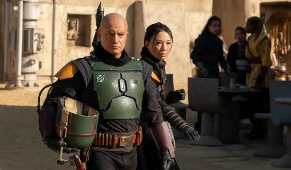 Boba Fett (Temuera Morrison) and Fennec Shand (Ming-Na Wen) walking through a Tatooine marketplace in the 2021 series The Book of Boba Fett.