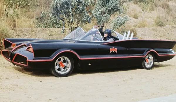 Burt Ward as Robin and Adam West as Batman riding in the colorful Batmobile on a dirt road in the 1960s Batman show