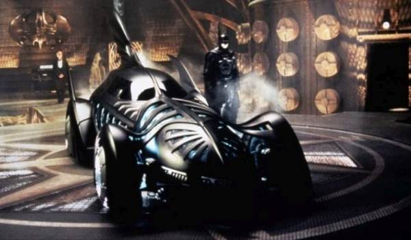 George Cooney as Batman in the Batcave standing next to the Batmobile in Batman & Robin (1997)