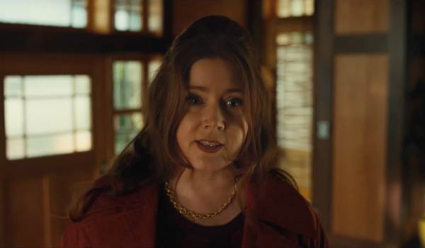Amy Adams as Chrissie in the movie Klara and the Sun, looking directly forward with a serious expression inside a wooden-paneled room