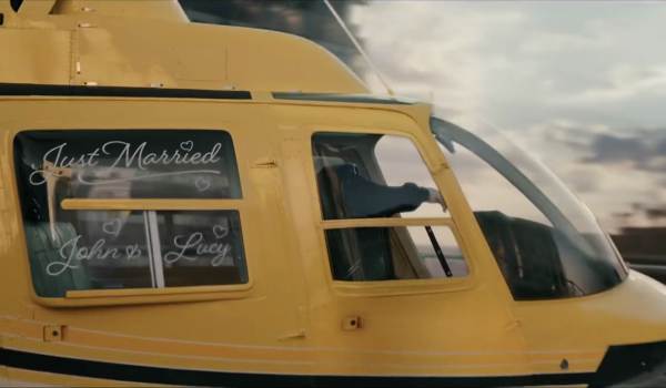 Side profile of a bright yellow helicopter with "Just Married" and "John & Lucy" written in white script on the windows, from a scene in Spider-Man: Brand New Day.