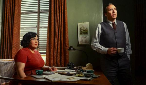 Karen Rodriguez as Janet Ruiz and Nicolas Cage as Ben Reilly looking off-camera in a 1930s-style office from the television show Spider-Noir.