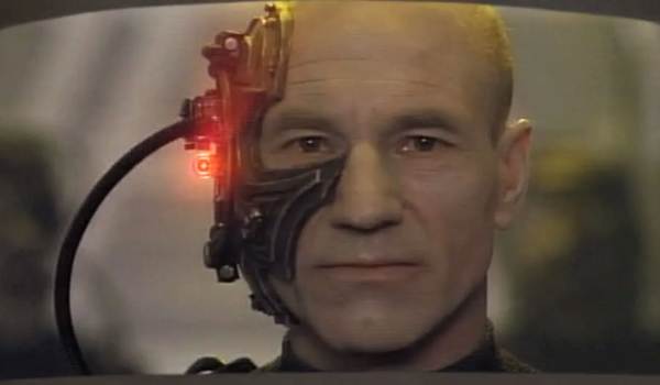 A close-up shot of Patrick Stewart as Captain Jean-Luc Picard assimilated as Locutus of Borg, showing mechanical implants covering the right side of his face with a glowing red light.
