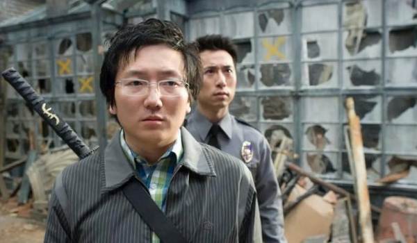Masi Oka as Hiro Nakamura, carrying a katana on his back, with a security guard in the background of the television series Heroes.