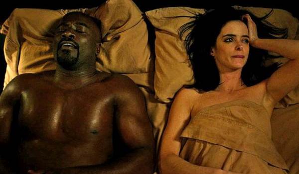 Krysten Ritter as Jessica Jones and Mike Colter as Luke Cage lying in bed together in the Marvel series Jessica Jones.