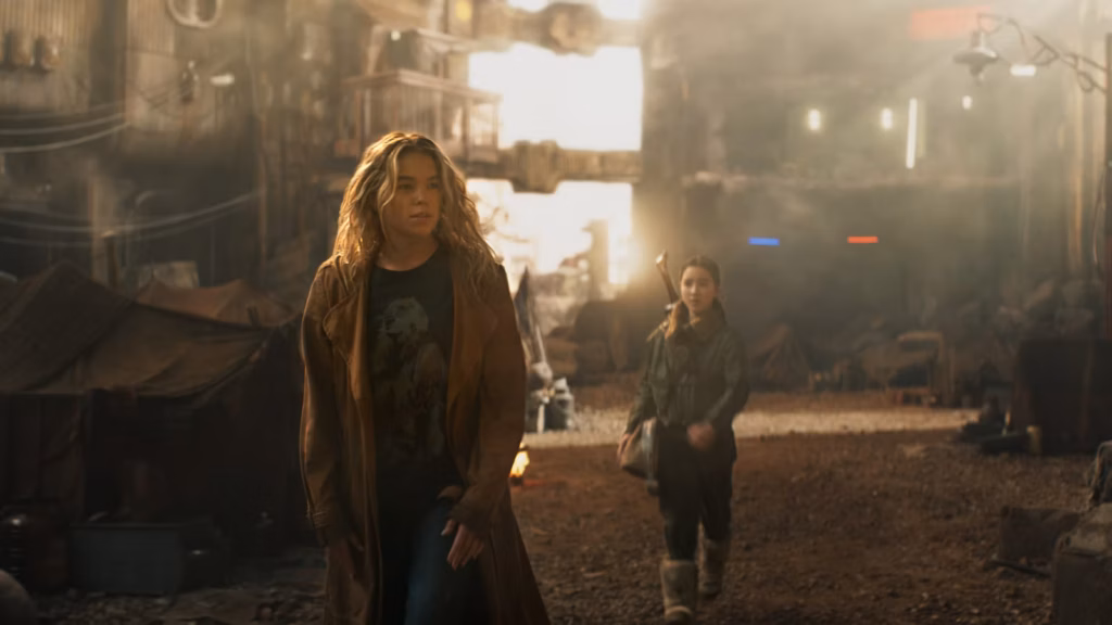 Milly Alcock as Supergirl and Eve Ridley as Ruthye Marye Knoll walking through the dusty, industrial streets of a desolate environment in the 2026 film Supergirl.