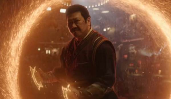 Benedict Wong as the Master of the Mystic Arts Wong, standing in front of a glowing orange magical portal while wielding mystical energy in the Marvel film Shang-Chi and the Legend of the Ten Rings.