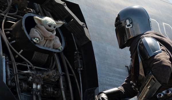 Din Djarin, played by Pedro Pascal, looking at Grogu sitting inside a mechanical compartment of his ship in the 2026 film Star Wars: The Mandalorian and Grogu.