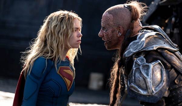 Milly Alcock as Supergirl and Matthias Schoenaerts as Krem of the Yellow Hills staring intensely at each other in a scene from the 2026 film Supergirl.